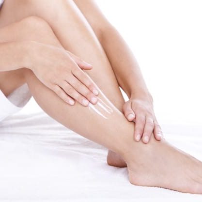 Woman applying moisturizer cream on the legs